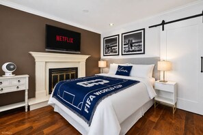 A bedroom with a bed, a fireplace, a TV, and framed pictures on the wall. - Modern 6BR |Near Downtown| Fast WiFi| Free Parking (Vancouver)