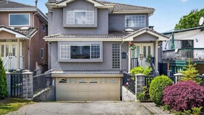 A two-story house with a garage, a front porch, and a well-maintained garden. - Modern 6BR |Near Downtown| Fast WiFi| Free Parking (Vancouver)