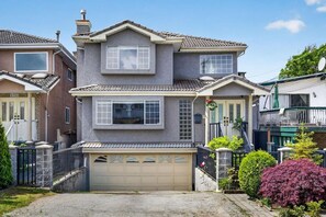 Ein zweistöckiges Haus mit Garage, Veranda und einem gepflegten Garten.