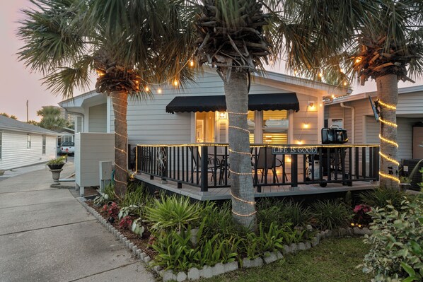 Uma casa com varanda, luzinhas e um letreiro que diz 'LIFE IS GOOD'.
