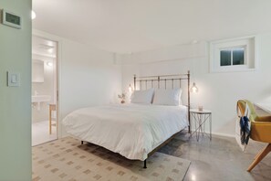 Une chambre à coucher avec un lit, une table de chevet, une lampe, une chaise et une fenêtre.
