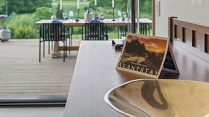 A wooden deck with a table set for dining, a bench, and a welcome sign for 'AVANTSTAY'. - Pool + Deck Dining + BBQ | Kayaks + EV Charger • Catskills View | River View (Germantown)