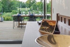 Une terrasse en bois avec une table dressée pour le repas, un banc et une pancarte d’accueil indiquant « AVANTSTAY ».