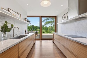 Une cuisine moderne avec des plans de travail en marbre, des meubles en bois et une vue sur un balcon.