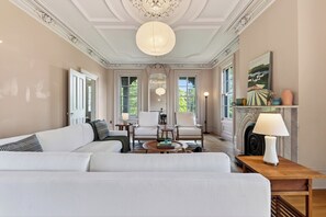 Un salon spacieux avec un canapé blanc, une table basse en bois et une cheminée.