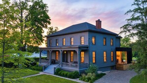 A two-story house with a porch, a chimney, and a small attached structure. - Pool + Deck Dining + BBQ | Kayaks + EV Charger • Catskills View | River View (Germantown)