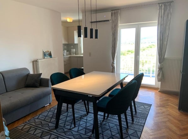 Un salon moderne avec un canapé, une table à manger, des chaises et une vue sur l’extérieur.
