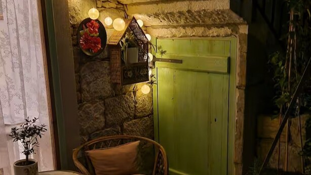 A cozy corner with a wicker chair, a small table, and a green door. - Diocletian Lux Apartment (Split)