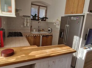 A kitchen with a gas stove, wooden cabinets, a sink, and a refrigerator. - Diocletian Lux Apartment (Split)