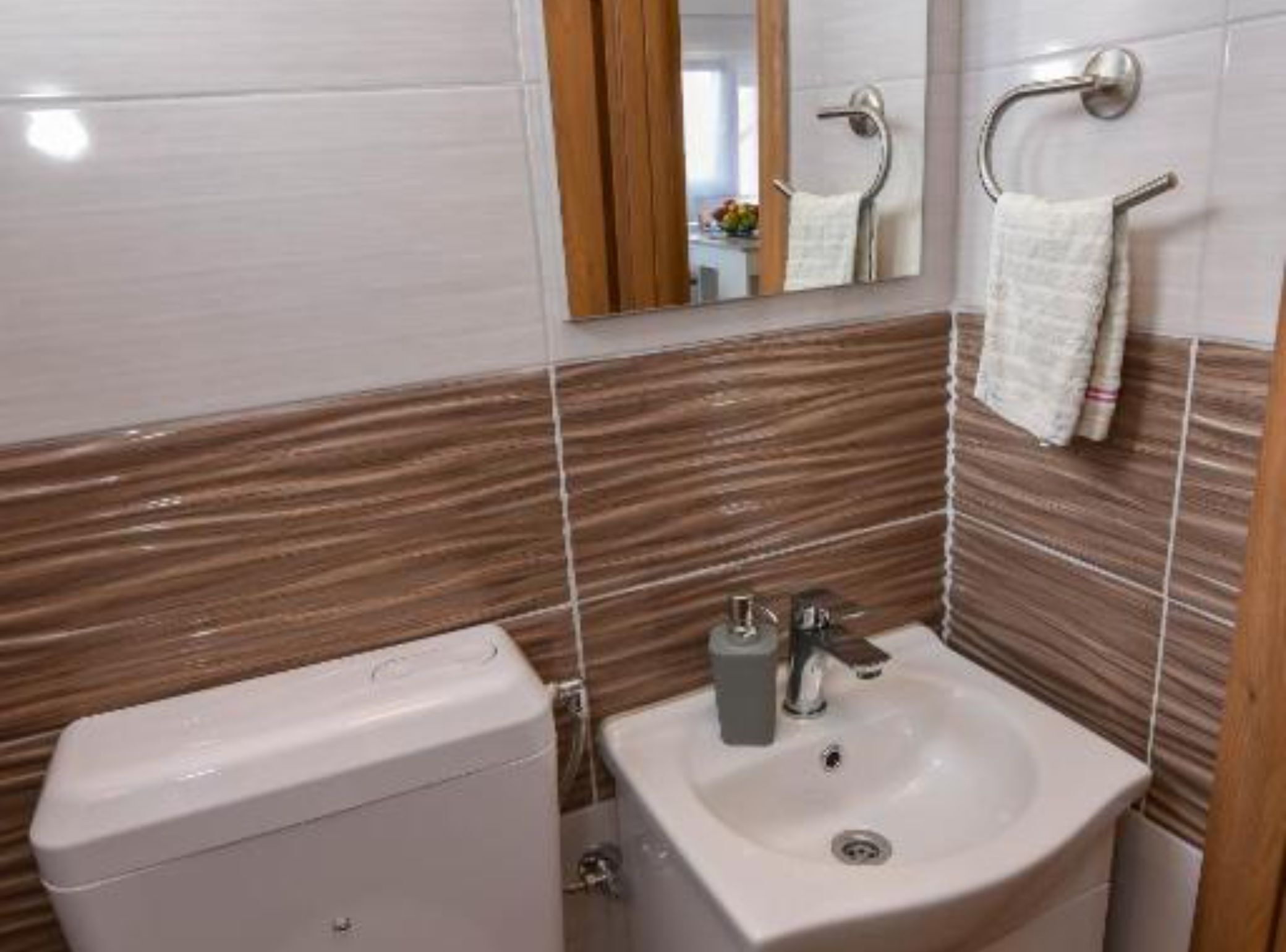 Un baño con inodoro, lavabo y perchero para toallas.