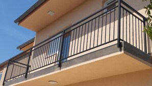 Un edificio de varios pisos con balcones, techo plano y cielo despejado.