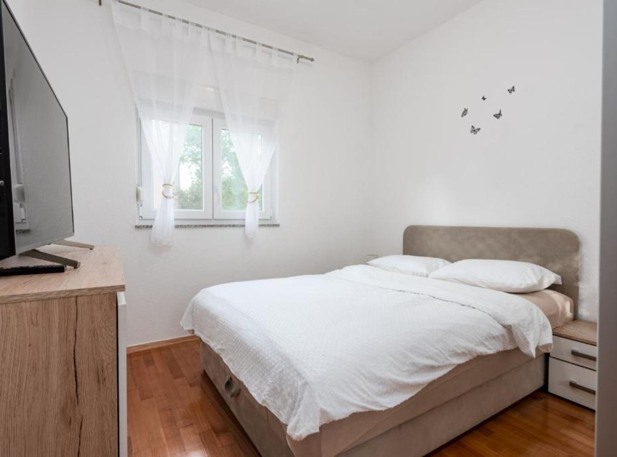 Una camera da letto con un letto, una scrivania, una finestra con tende e una parete decorata con farfalle.