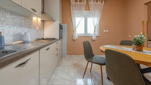 Moderni keittiö, jossa on kaasuliesi, pesuallas sekä ruokailutila pöytineen ja tuoleineen.