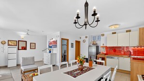 Une cuisine moderne avec des meubles blancs, un pare-feu rouge et un lustre.