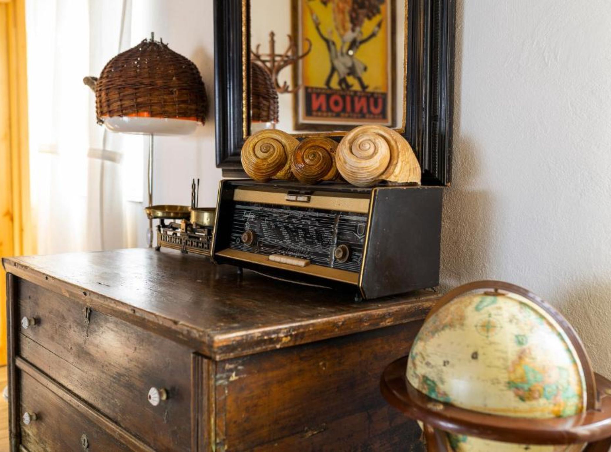 A wooden dresser with a vintage radio, a globe, and a framed poster.