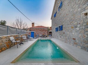 Ein Swimmingpool mit Liegestühlen und ein Gebäude mit blauen Fensterläden.