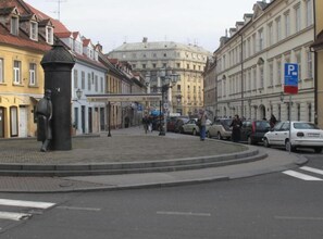 Eine Stadtstraße mit Gebäuden, einer Statue und geparkten Autos.