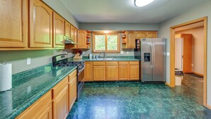 A kitchen with wooden cabinets, a stainless steel refrigerator, and a green marble countertop. - Wooded Applegate Retreat w/ Private Trail Access (Applegate)