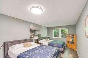 A bedroom with two beds, a nightstand, a wooden cabinet, a window with a view, and a ceiling light. - Waterfront Union Getaway w/ Ocean & Mtn Views (Union)