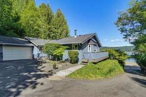 A two-story house with a garage, a covered porch, and a view of a lake. - Waterfront Union Getaway w/ Ocean & Mtn Views (Union)