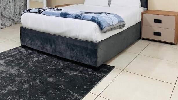 Une chambre à coucher comprenant un lit, des tables de chevet, une commode, une coiffeuse et un tapis.