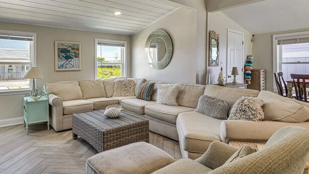 A living room with a sectional sofa, a coffee table, and a herringbone-patterned floor. - Red, White & Beach! 5BR Atlantic Beach Cottage (Atlantic Beach)