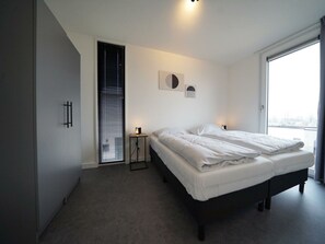 Een slaapkamer met een bed, nachtkastjes, een raam en een deur.