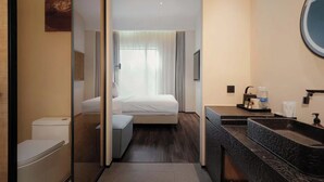 A hotel room with a bed, a toilet, a sink, and a mirror. - M Hotel (Hangzhou)