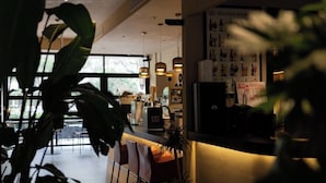 A modern kitchen with a bar area, potted plants, and a view of the outdoors. - M Hotel (Hangzhou)