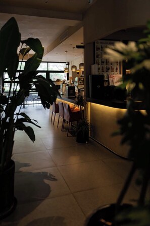 A modern kitchen with a bar area, potted plants, and a view of the outdoors. - M Hotel (Hangzhou)