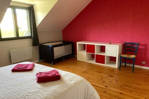 Une chambre avec un plafond en pente, un lit, un bureau, une chaise et une fenêtre.