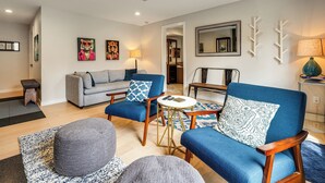 Ein modernes Wohnzimmer mit einer Couch, Sesseln, einem Couchtisch und einem Teppich.