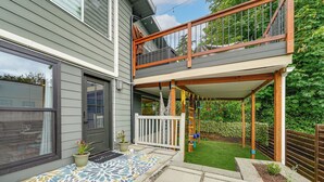 Ein zweistöckiges Haus mit Balkon, Eingangstür und kleinem Garten.