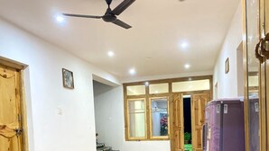 Une pièce spacieuse avec un plancher en bois, un ventilateur de plafond et un réfrigérateur violet.