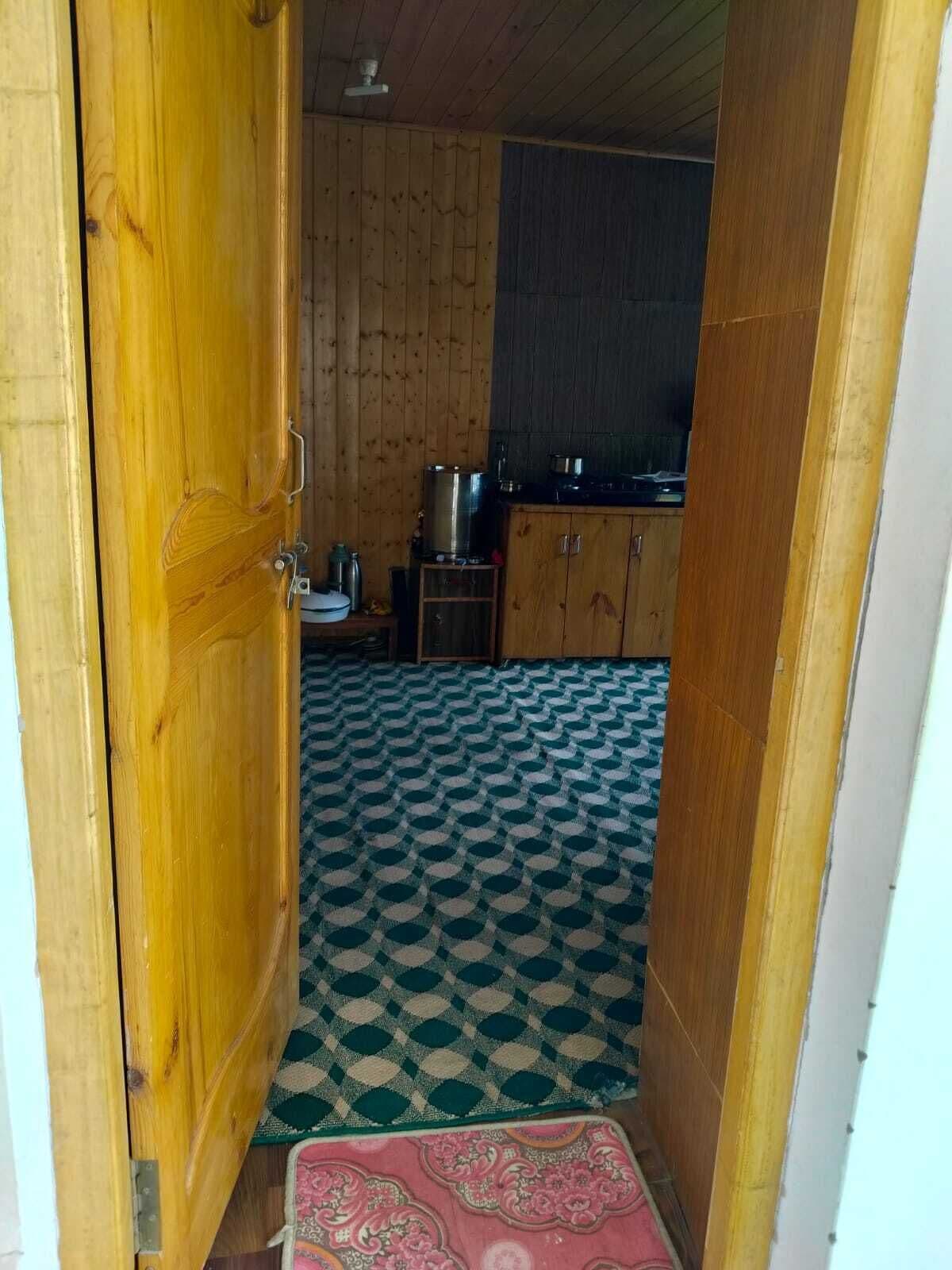 A narrow hallway with a patterned floor, wooden walls, and a kitchen area with cabinets and appliances.