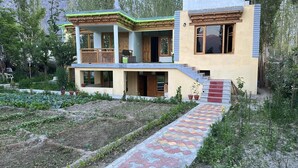 Une maison à deux étages dotée d’un balcon, d’un petit jardin et d’un chemin dallé menant à l’entrée.