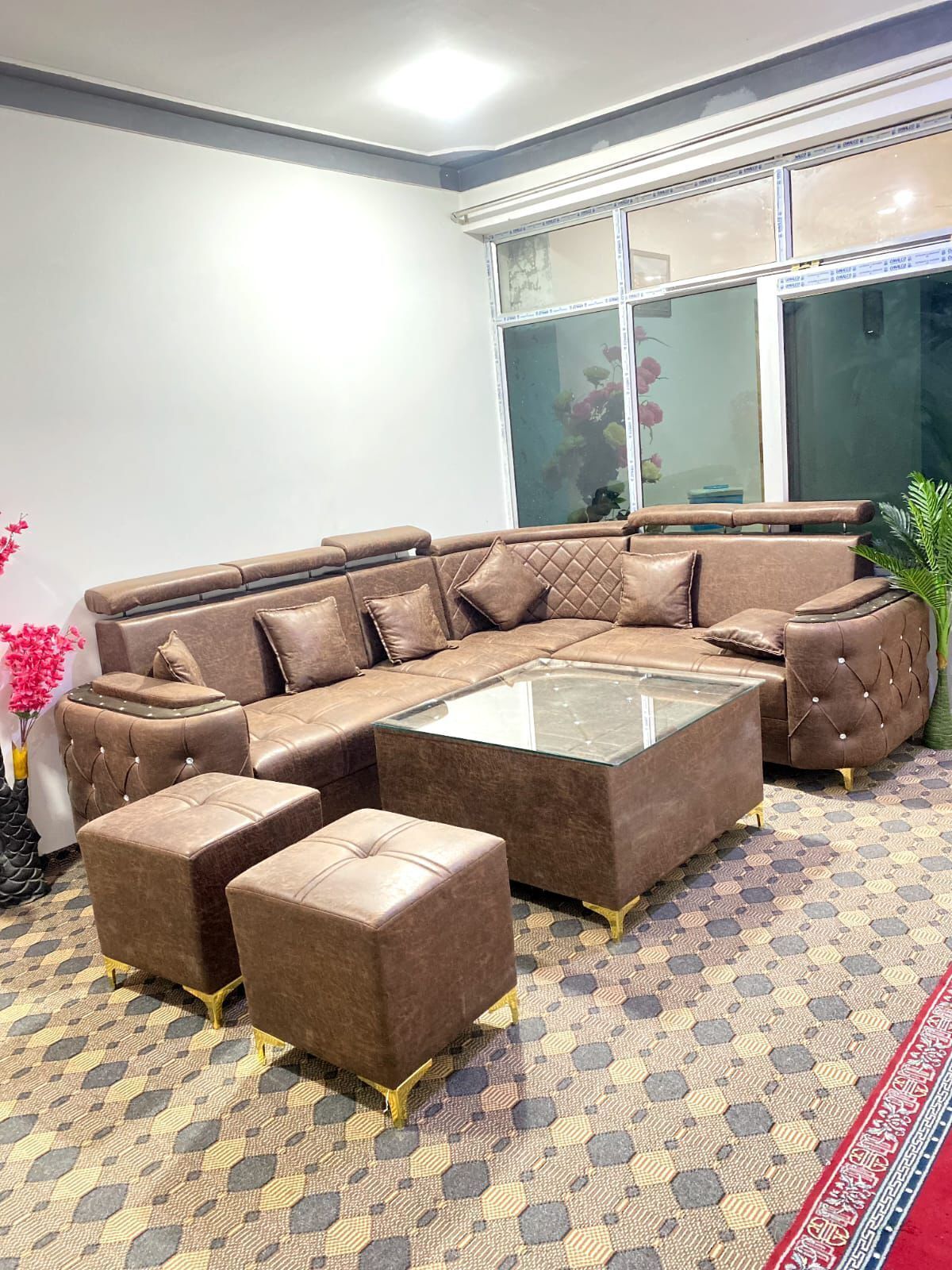 A modern living room with a sectional sofa, ottomans, and a glass coffee table.