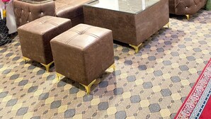 Una sala moderna con un sofá modular, otomanas y una mesa de centro de vidrio.