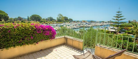 Eine Terrasse mit Blick auf eine Marina, ein Stuhl und eine Blumenwand.