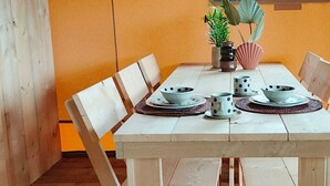 A dining table with chairs, plates, bowls, and mugs. - Holiday Home in Noord-scharwoude With Wi-fi (Noord-Scharwoude)
