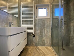 A modern bathroom with a shower, a built-in sink, and a towel rack. - Holiday Home in Dordrecht With Terrace (Dordrecht)