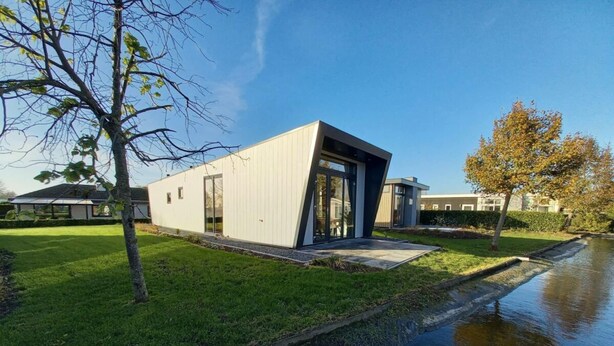 A modern building with a sloped roof, large windows, and a grassy area in front. - Holiday Home in Dordrecht With Terrace (Dordrecht)