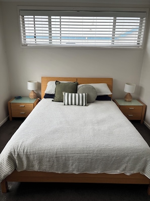 Una camera da letto con un letto, due comodini, una finestra con persiane e vista sull'esterno.