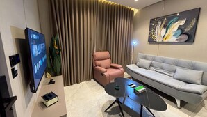 A modern living room with a flat-screen TV, a sofa, a pink chair, a coffee table, and a large painting on the wall. - 405 tara-JRE Jabal Al Lweibdeh with stunning view (Amman)