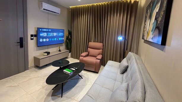 A modern living room with a flat-screen TV, a sofa, a coffee table, and a chair. - 405 tara-JRE Jabal Al Lweibdeh with stunning view (Amman)