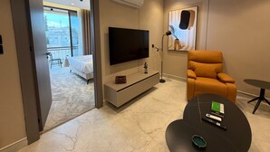 Une chambre d’hôtel moderne équipée d’un lit, d’un téléviseur à écran plat, d’un canapé, d’une petite table et d’un balcon avec vue.