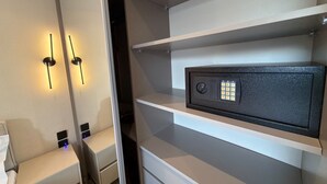 Une chambre d’hôtel avec un lit, une table de chevet et un coffre-fort placé sur une étagère.
