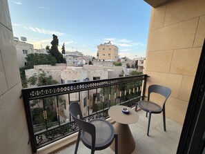 A balcony with two chairs and a table, overlooking a cityscape with buildings and trees. - 411 tara-JRE Jabal Al Lweibdeh with stunning view (Amman)