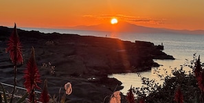 Un coucher de soleil sur une côte rocheuse où la végétation est rare.