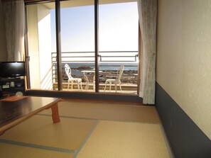 Una habitación con un gran ventanal corredizo que da a un balcón con vistas al océano.